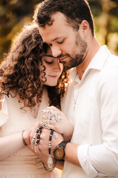 couple embracing while holding Catholic rosary beads