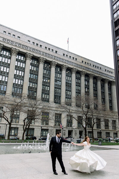bride laughing and dancing with groom outside of chicago city hall