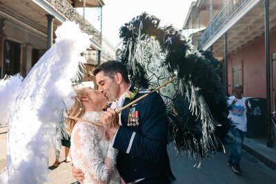 Bride a groom celebrate on bourbon street in new orleans with umbrellas and a parade