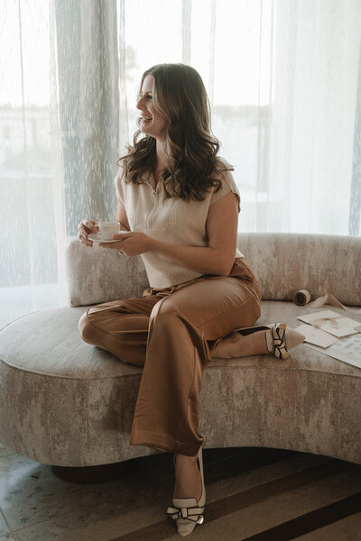 Southern California wedding planner casually sitting on a sofa, holding a cup of espresso
