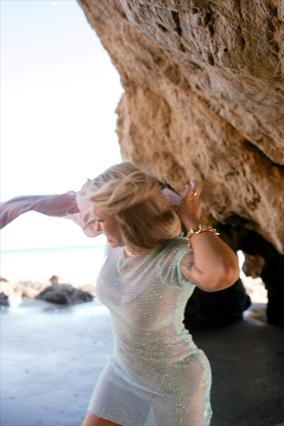 Nicky Lynn dancing on the shoreline in a blue dress, expressing freedom, joy, and emotional release