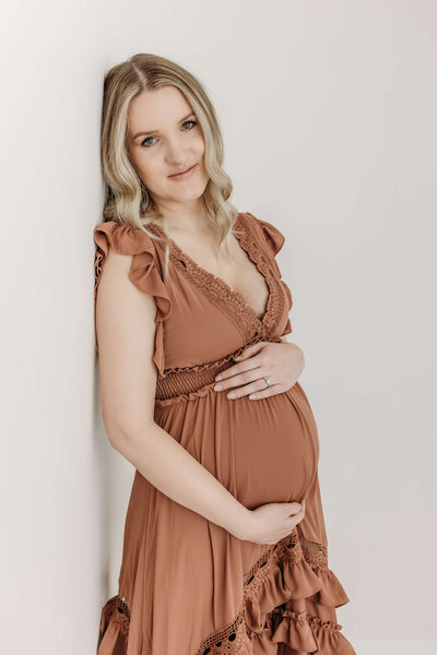 Eau Claire photographer session of expecting mom in beautiful rust colored dress in studio