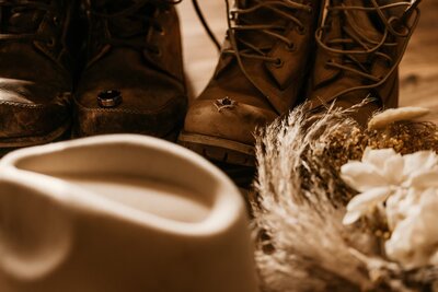 Bride and groom's hiking boots lined up with wedding bands in wedding detail photo.