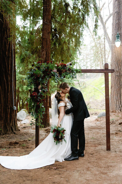 bride and groom kissing under altar by wedding videographer and photographer tampa