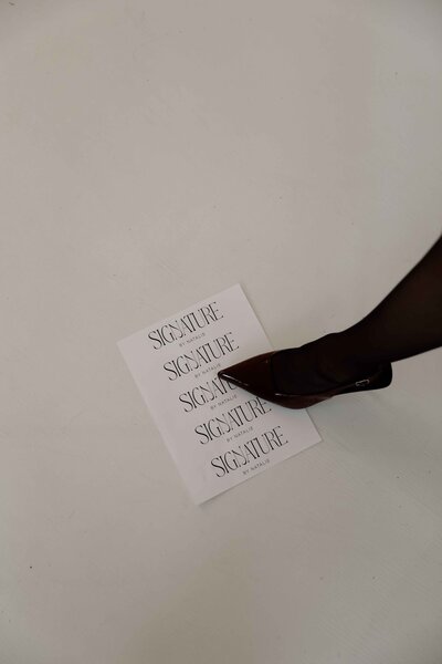 Natalie Jones stepping on a white piece of paper that has her "Signature by Natalie" logo on it