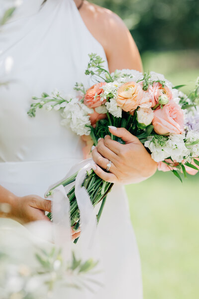 a bride holding a bouquet with peach roses