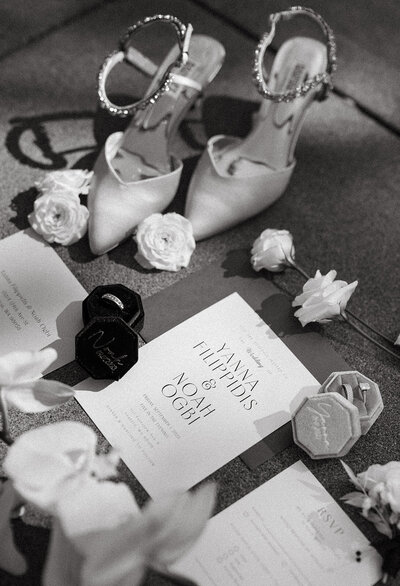 Wedding shoes, invitations, and rings arranged on the floor.