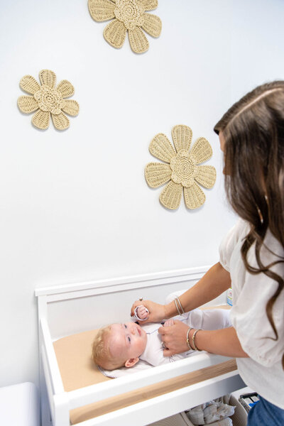 Woman holding her babies arms on a changing table