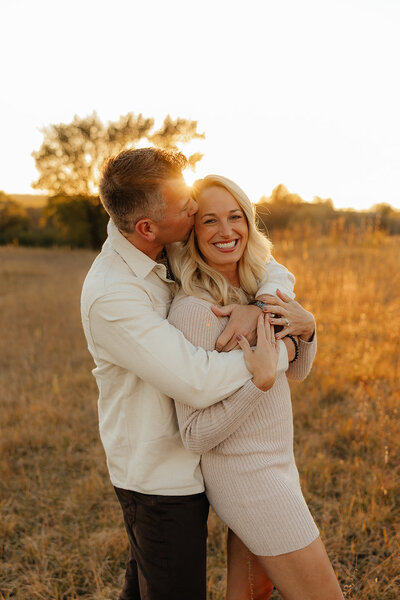 man and woman kissing holding pregnant belly