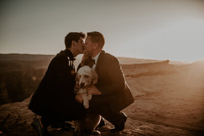 couple kissing and holding dog