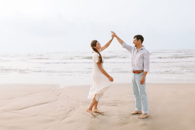 Photo of bride and groom twirling on the beach in Port Aransas