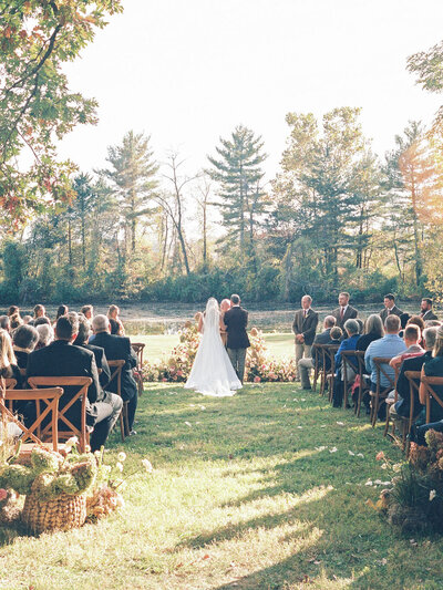 Backyard wedding ceremony overlooking water and trees with basket arrangements Maryland Eastern Shore estate