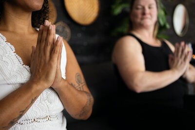 Katie and client with palms together for guided meditation.
