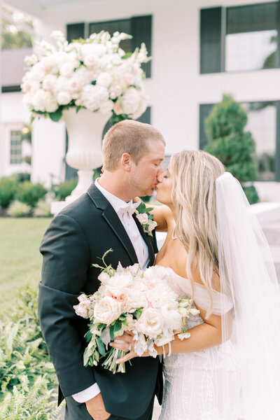 Bride and Groom in front of Houston's Venue with gorgeous wedding flowers