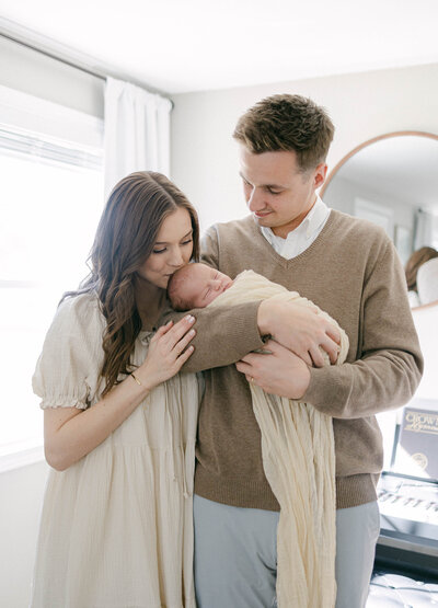 women kissing newborns head while man holds baby and smiles knoxville tennessee newborn photographer