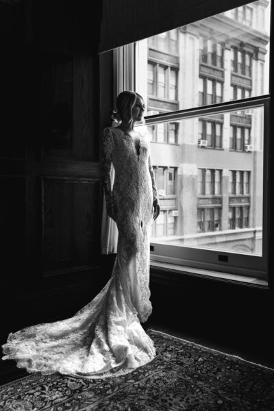 woman in wedding dress standing by window