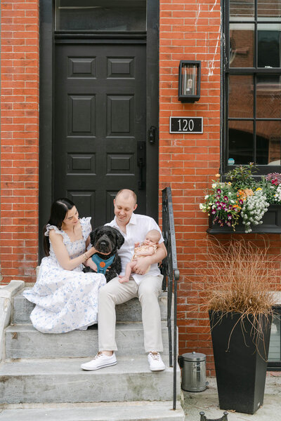 Philadelphia couple holds newborn baby and cuddles their dogs