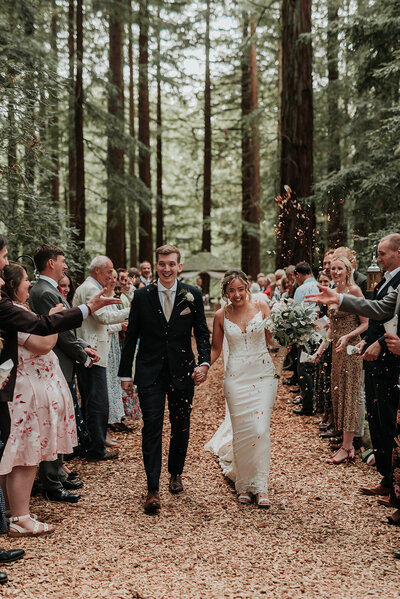 Bride & Groom walking down the aisle as confetti is thrown in the Redwoods at Two Woods Estate, Pulborough