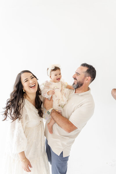Mom and dad smiling while baby enjoys smash cake during Miami session.