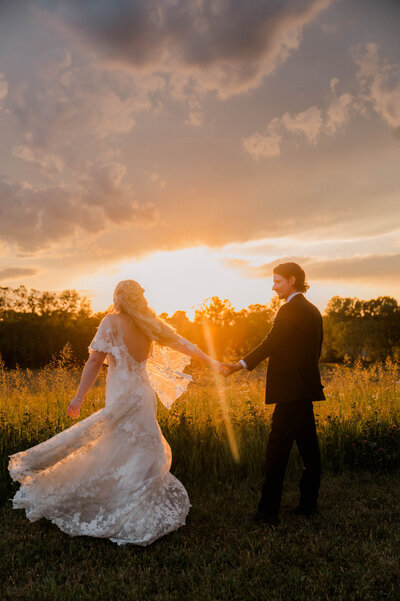 Wedding bridal party poses for the camera outside while smiling at one another, bride and groom kiss.