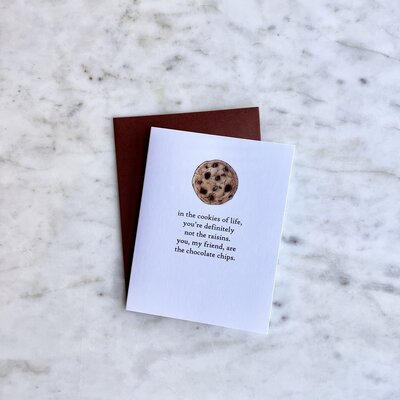 Card with an illustration of a chocolate chip cookie that reads "in the cookies of life, you're defiantly not the raisins. you, my friend, are the chocolate chips."