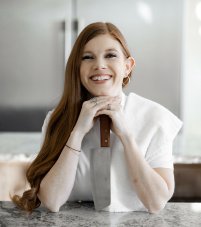 woman in chef's uniform holding knife smiling at camera