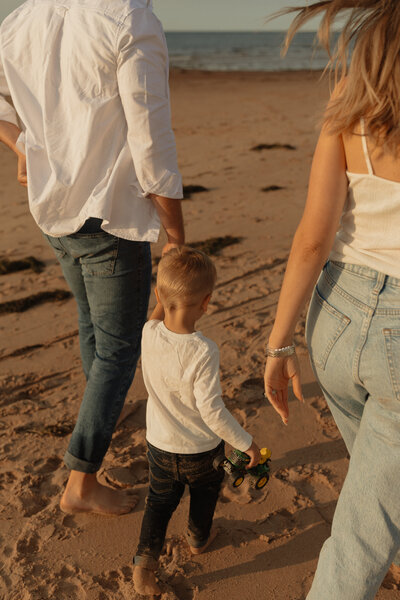 mom dad and son walking on beach in pei for lifestyle photos