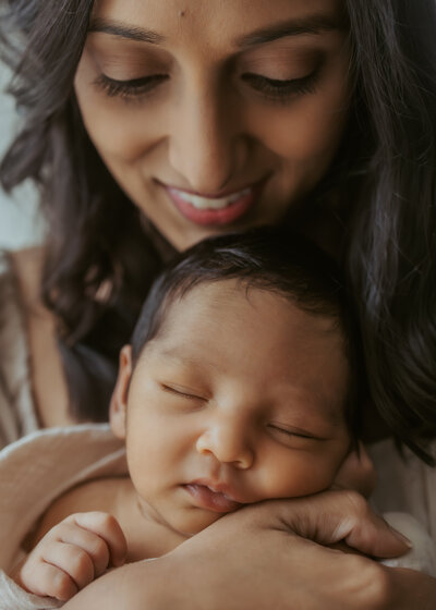 First time parents facing each other and kissing while their beautiful baby girl sleeps in between their arms.