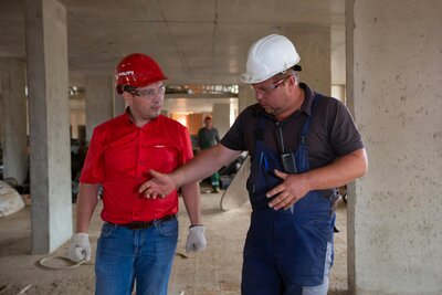 Two workers in hard hats discussing a job, representing accountability and ownership in high-performance teams