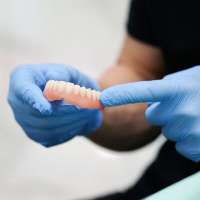 Prosthodontist holding a complete denture for a patient referred to us at Peak Prosthodontics. Serving Lethbridge, Alberta and nearby areas.