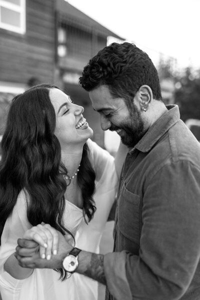 A couple laugh and smile while dancing. 