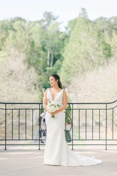 Woman standing on terrace for bridal portrait session in wedding dress