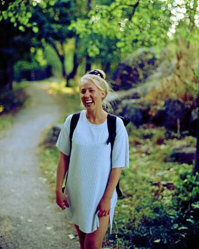 mielen paremminvoinnin ja kehomieliyhteyden valmentaja metsätiellä seisten katsoo kameraan hymyillen