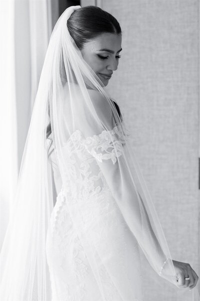 A person in a wedding dress with a veil flowing over their shoulder 