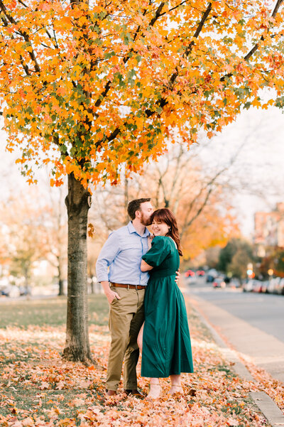 Woman embraces fiance in orange dress for engagement session.