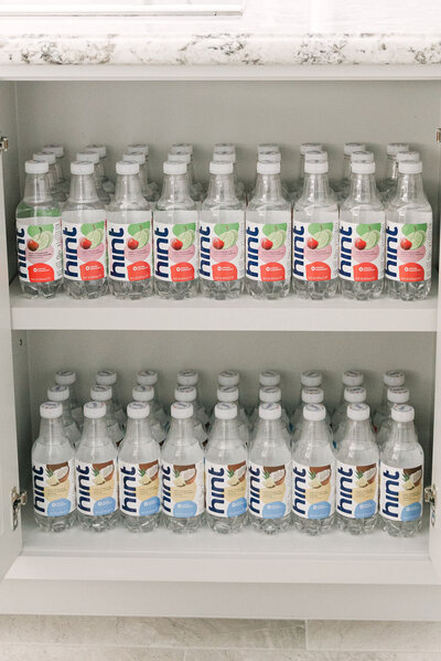 Hint water in various flavors organized on shelves in a white kitchen cabinet