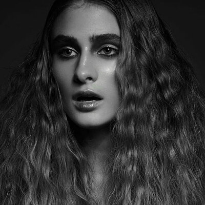 Editorial image of client with wavy, styled hair that has a lot of volume.