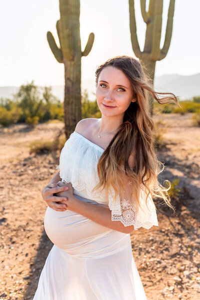 arizona mom with two daughters hugging her maternity belly in lake pleasant for photography session