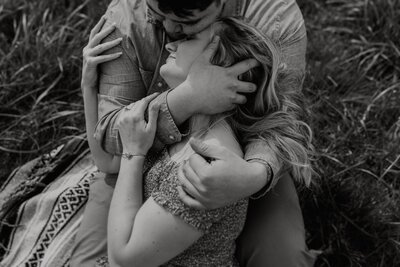 Bride and groom holding each other tight on on the Oregon Coast as the wind whips her long hair 