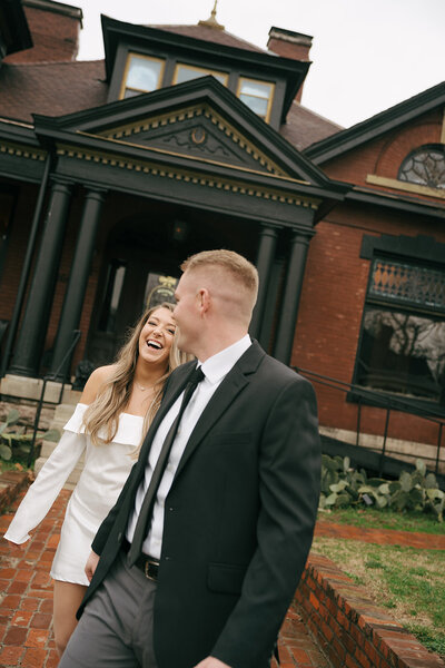 A bride and groom walking after their wedding ceremony in Austin, Texas. The bride is holding her flowers, the groom is holding her dress. 