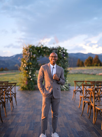 owner of JKG Photography in black and white with a black turtle neck sitting down on a sofa chair smiling , Colorado Wedding Photographer of JKG Photography