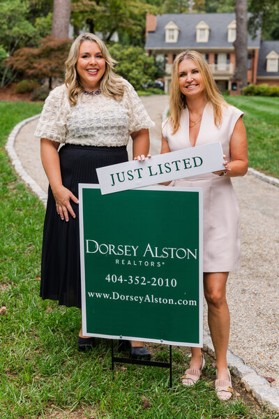 real estate agents women team holding a Just Listed sign in front of a house during photoshoot with Laure Photography Atlanta