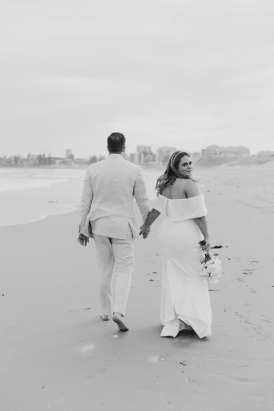 bride and groom walking along a beach