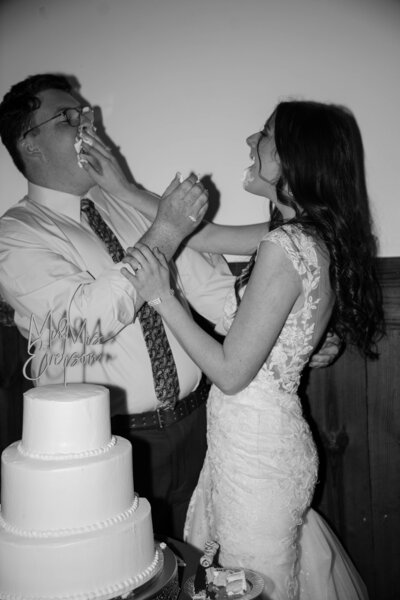 Husband and wife put icing on each other during their cake cutting.