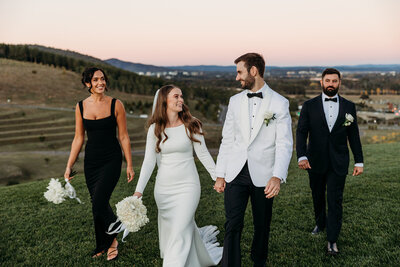 Bride and groom walking at sunset with their maid of honour and best man behind them. View of Canberra in the background