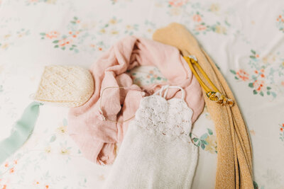 newborn outfits and swaddles laid out on a floral backdrop showcases what kate mccord photography offers for all inclusive newborn photography in harrisburg pa