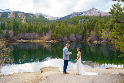 Bride and groom exchanging vows beside a lake with mountain views during their Breckenridge, Colorado elopement ceremony.