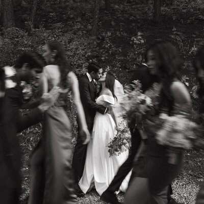The bride and groom snuck away to shared a kiss during their bridal party photos. The motion blur captures the busyness of a wedding day.