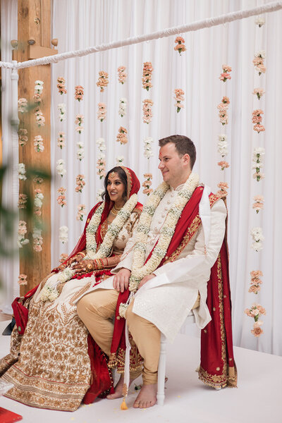 brick backdrop with green and white tropical greenery and roses, couple at ceremony altar in summer