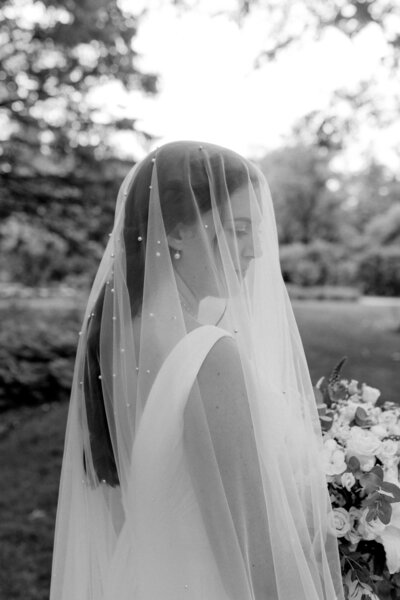a bride posing with her veil over her face